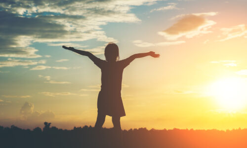Silhouette of little girl raising hand to freedom happy time